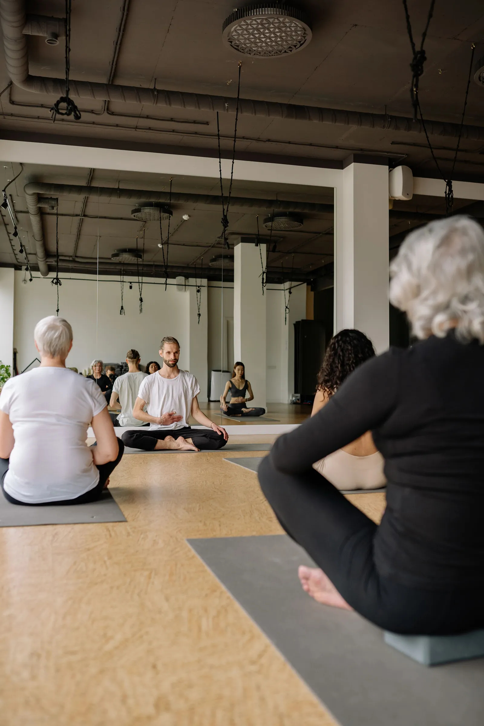 Grupo sentado em meditação numa aula de yoga